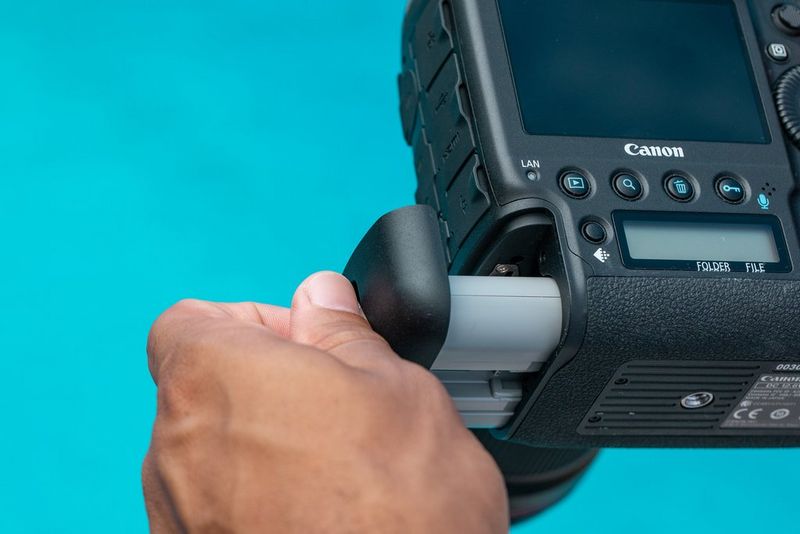 Removing the battery at the bottom-left of a Canon EOS-1D X Mark III.