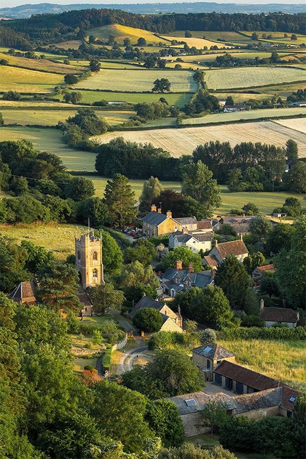 The tower of the church and surrounding houses nestle among greenery in the village of Corton Denham in Somerset, England.
