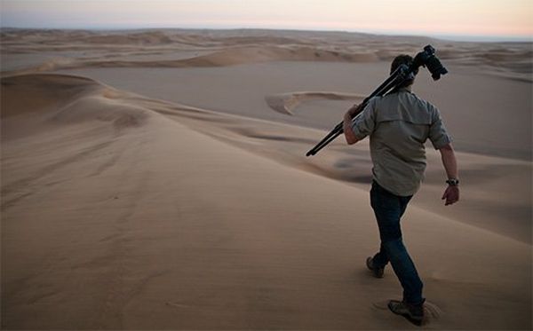Brent Stirton strides across the desert at dusk with his camera, as Spencer MacDonald films him using a Canon EOS C200.