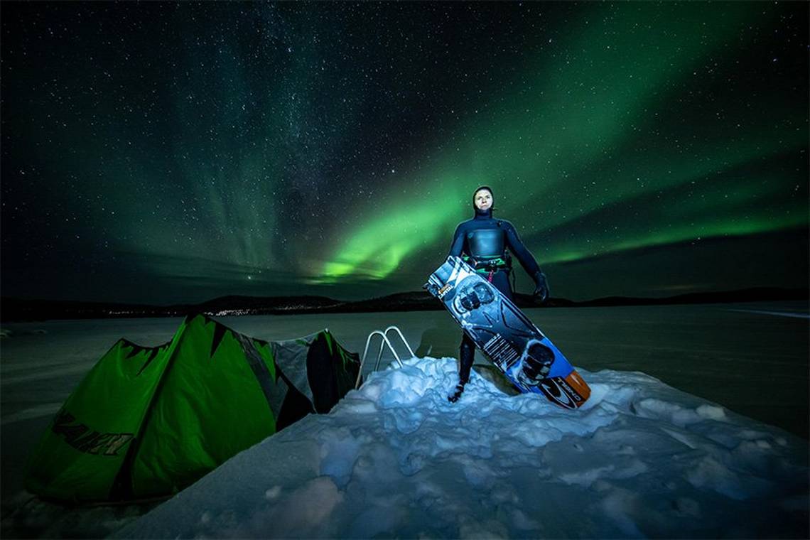 Professional kite surfer Kevin Langeree with his board in front of an Aurora Borealis-filled sky. Photo by Humberto Tan.
