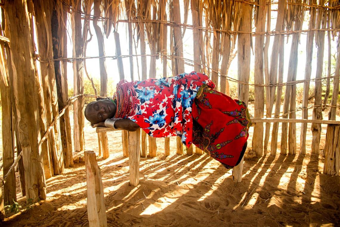 A woman sleeps on a narrow bench in a wooden hut in the all-female Umoja village in northern Kenya.