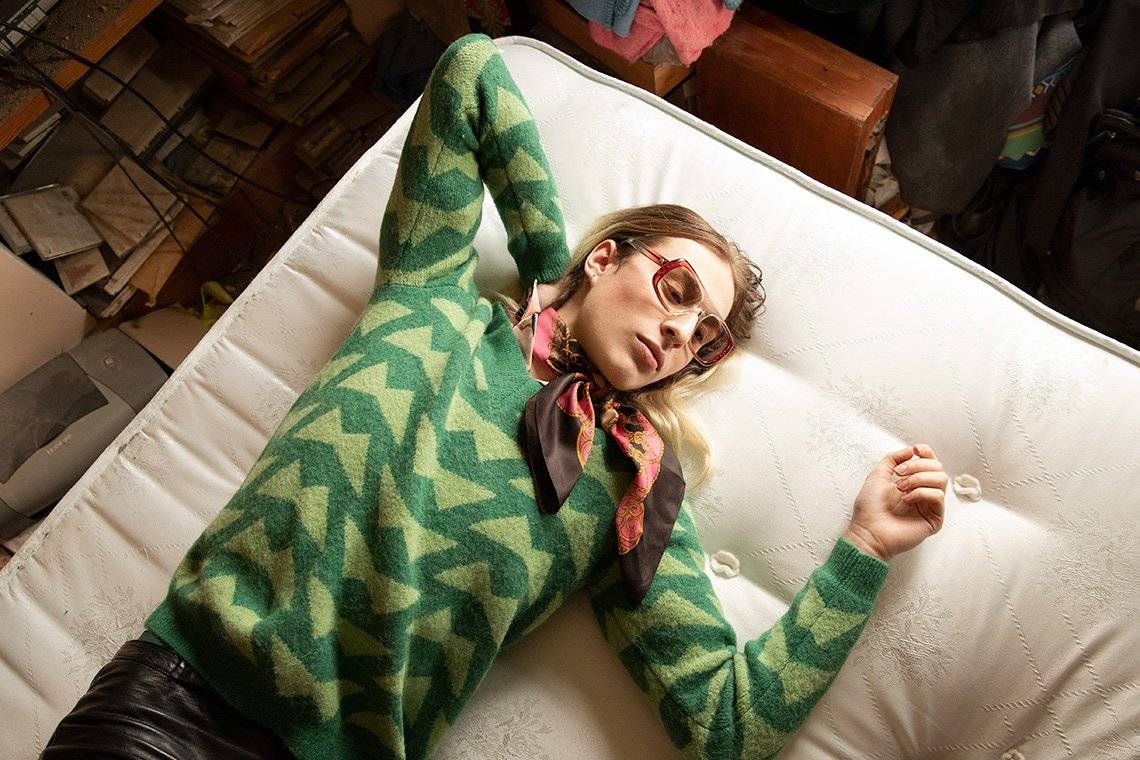 An androgynous long-haired model wearing a striped top and scarp lies on a bed. Photo by Wanda Martin on a Canon EOS-1D X Mark II.