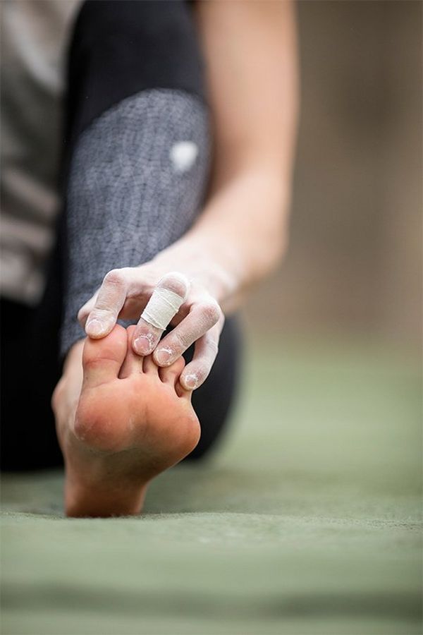 An athlete flexes her toes back with her fingers.