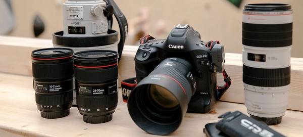 A Canon EOS-1D X Mark II camera with EF 85mm f/1.4L IS USM lens and various other Canon lenses beside it.