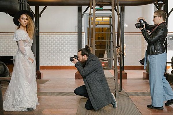 Two photographers point their Canon cameras at a bride to take her portrait. 