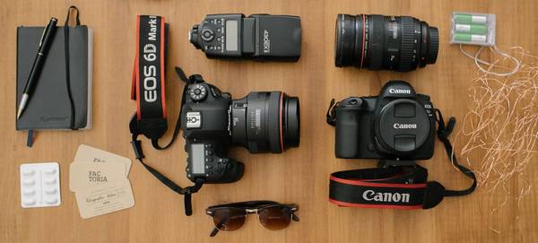 On a table are two Canon DSLRs, lenses and accessories.