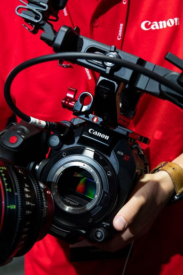 A Canon expert holds a camera and demonstrates it to visitors at IBC 2019.