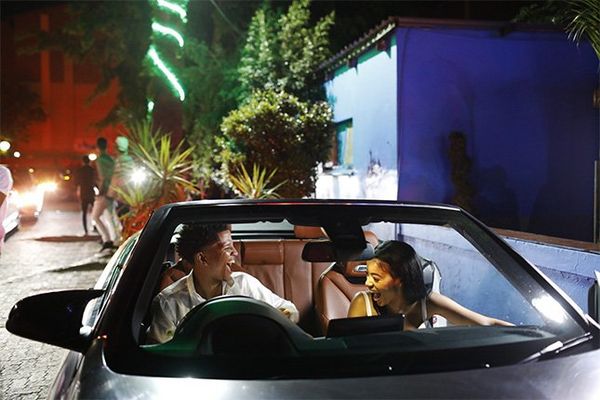 An affluent young couple in an expensive open-top car.