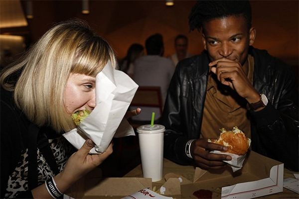 A young couple eating hamburgers.
