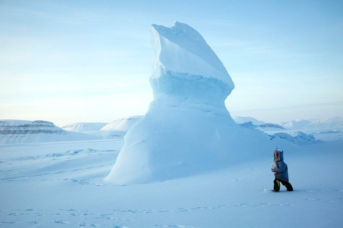A man walking in the bleak Arctic landscape.