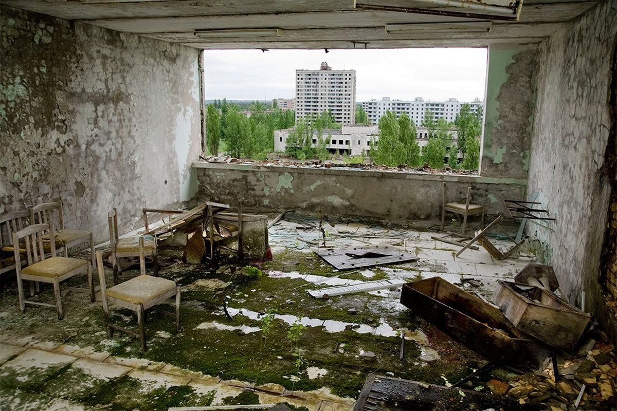 A room strewn with discarded furniture and rubble, its bare concrete walls peeling.