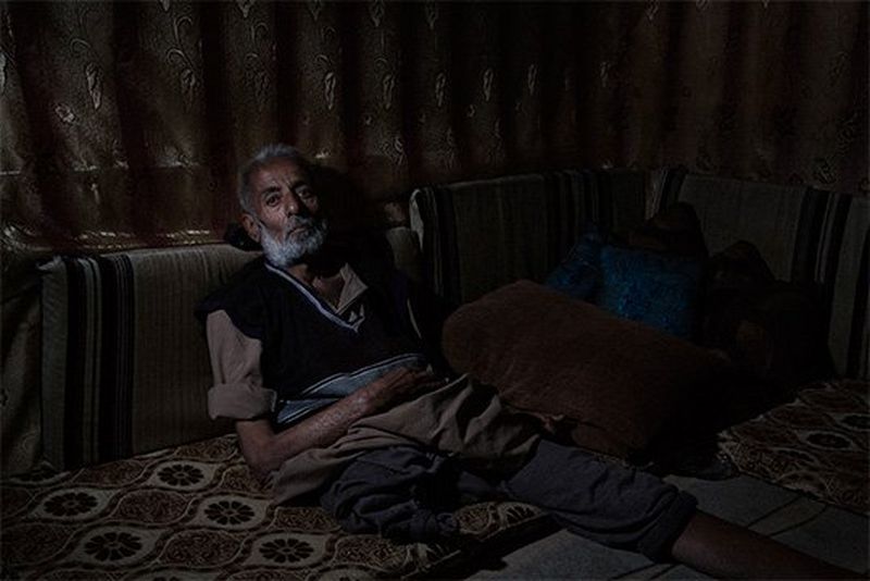 A man who has lost one legs leans against some cushions in a shabby makeshift tent in Lebanon.