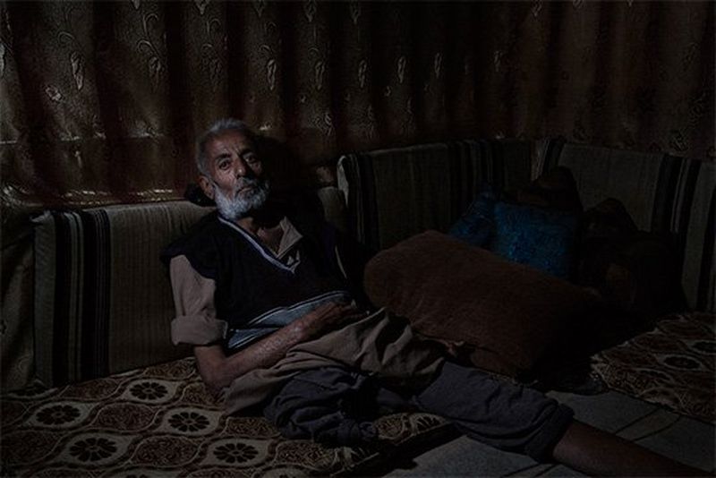 A man who has lost one legs leans against some cushions in a shabby makeshift tent in Lebanon.