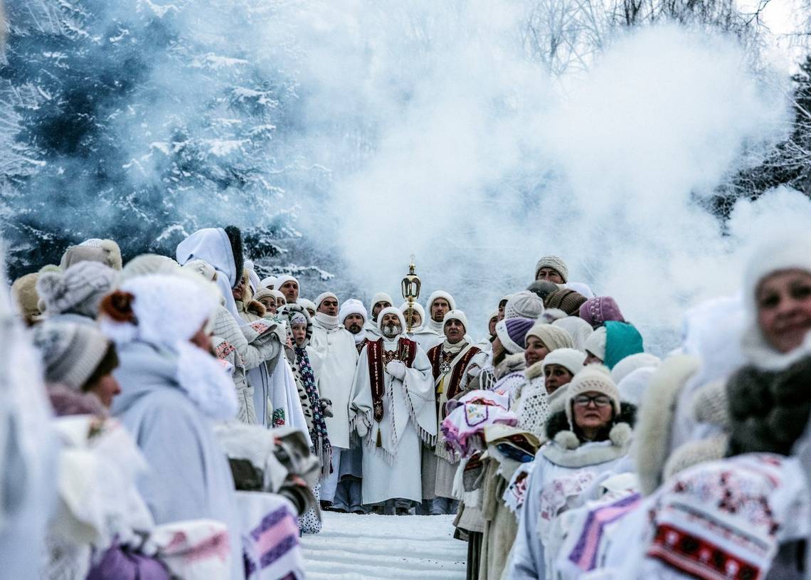 Members of the Church of the Last Testament stand in white robes in front of snow-covered trees. Photo by Jonas Bendiksen.