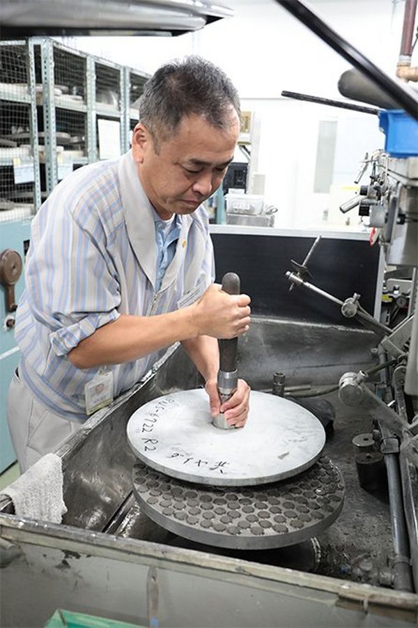 Toshi Saito hand-grinds lens polishing tools.