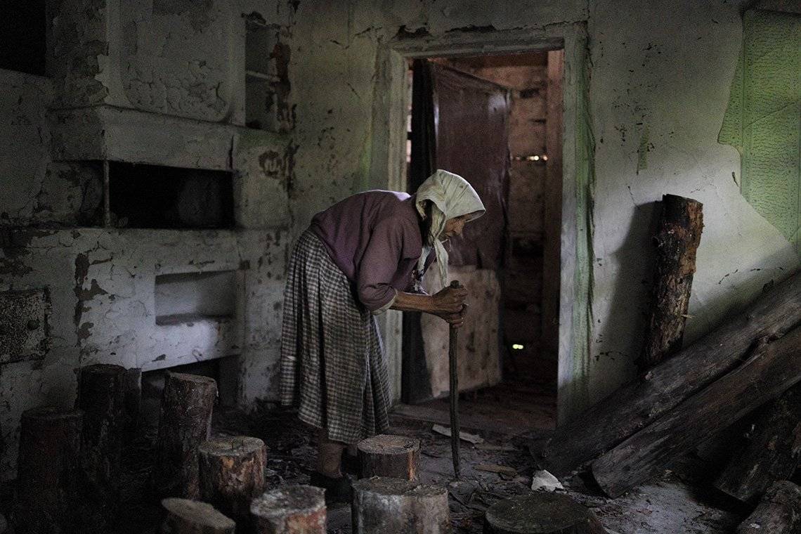 A hunched woman in a derelict house in Chernobyl.