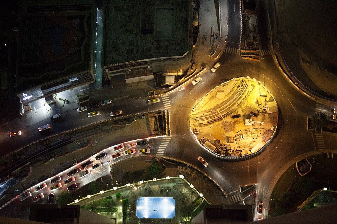 An overhead view of a busy road junction at night, photographed by Olivia Arthur.