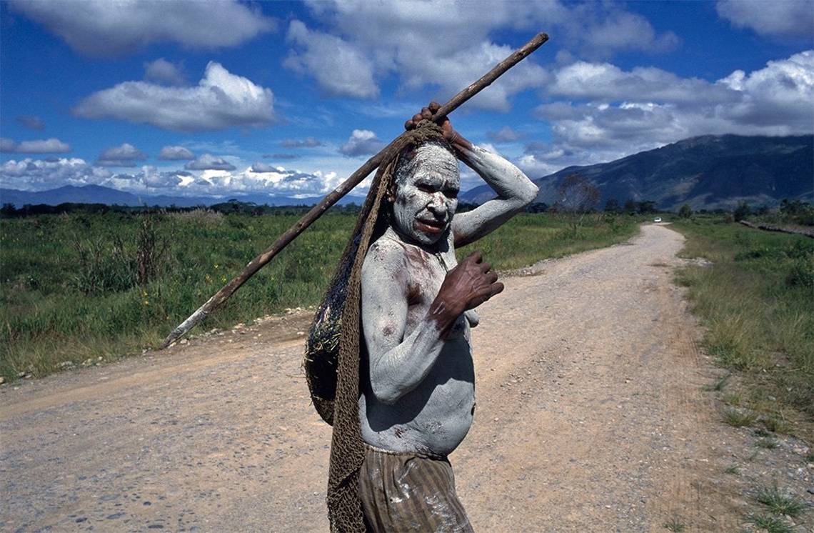 An indigenous tribeswoman in Papua covered in white mud. Photo by Susan Meiselas.