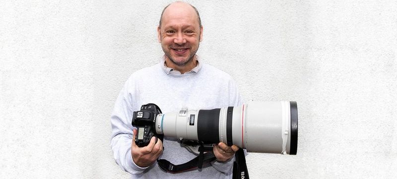 Sports photographer Marc Aspland holds a Canon camera and telephoto lens.