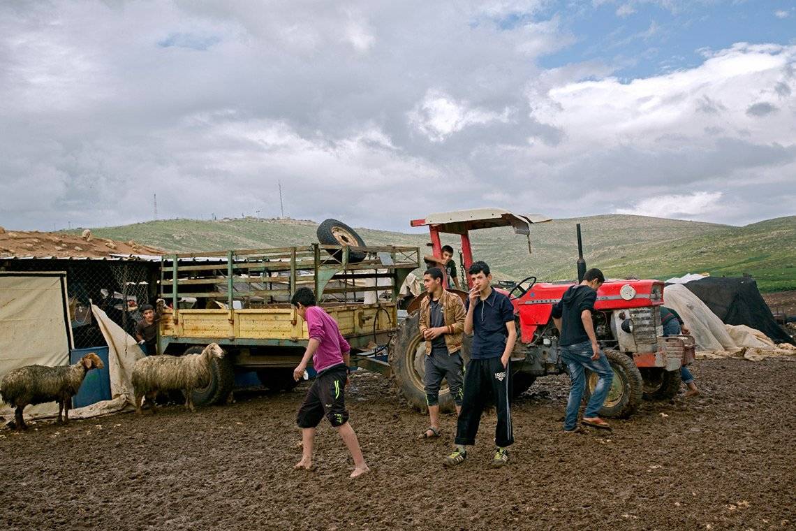 Mashid Mohadjerin's spontaneous shot: teenagers mill around a tractor and trailer in a muddy field, one of them smoking.