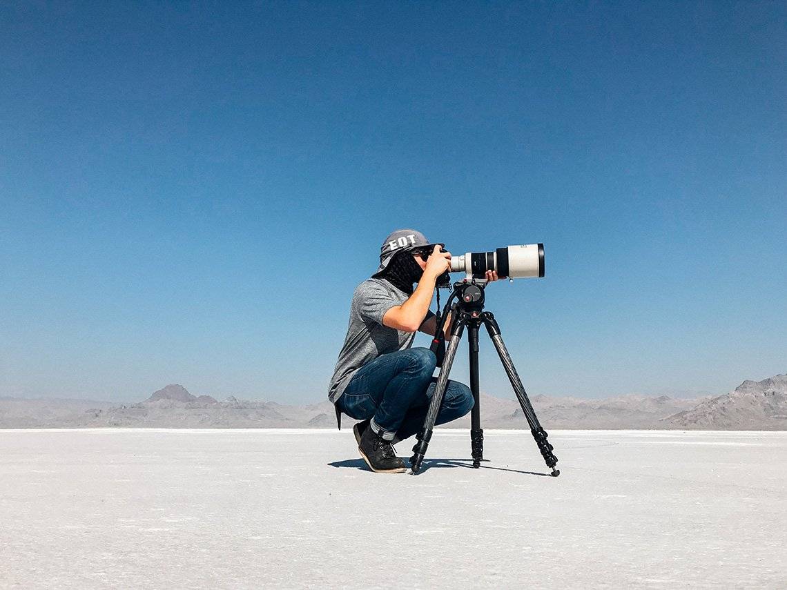 Photographing a cycling world record: Matt Ben Stone crouches behind his Canon camera and lens on a tripod in Utah salt flats.
