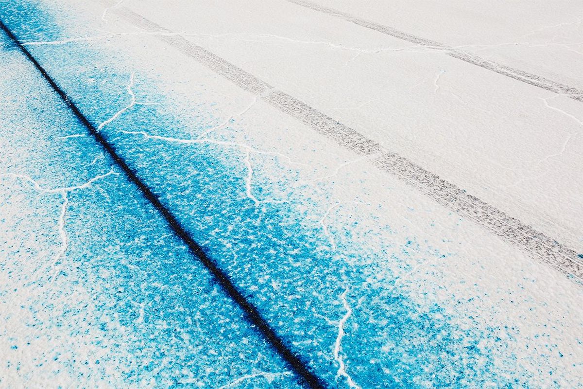 A dark blue line and larger turquoise line through white cracked salt flat.