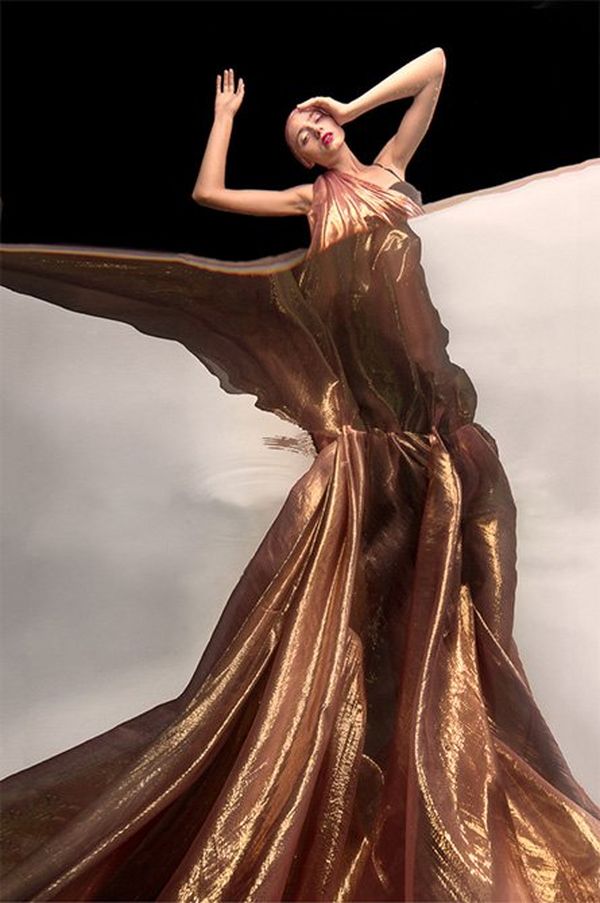 A woman draped in gold fabric, with half her body seen from underwater.