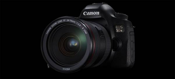A Canon EOS 5DS DSLR with a zoom lens is seen against a black background.