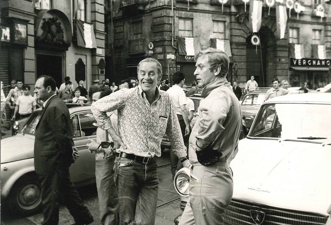 Michael Deeley and Michael Caine leaning on minis in Italy.