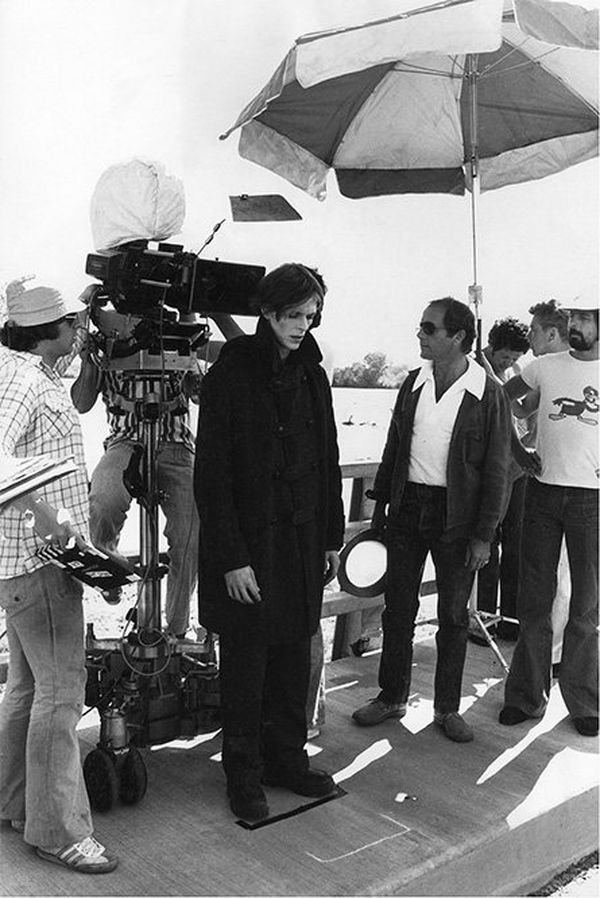 David Bowie in costume as Thomas Jerome Newton on the set of The Man Who Fell to Earth, surrounded by the film crew.