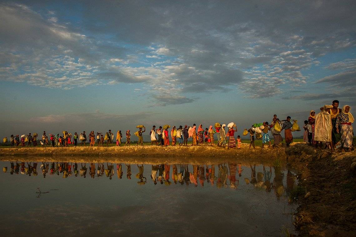 A line of Rohingya Muslim people carry bags of possessions. Photo by Salahuddin Ahmed on a Canon EOS 5D Mark II.