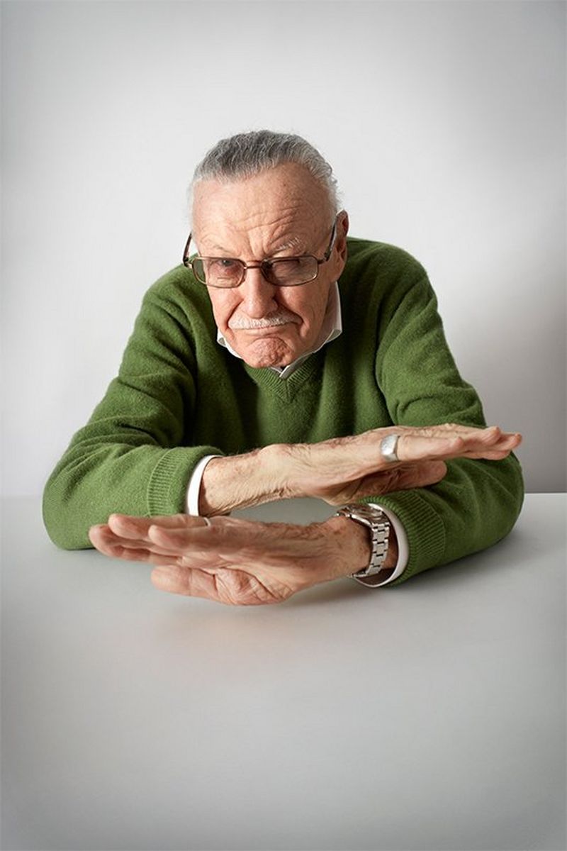Stan Lee sits at a table gesturing with his hands as if telling a story. Portrait by Lorenzo Agius on a Canon EOS 5D Mark III.