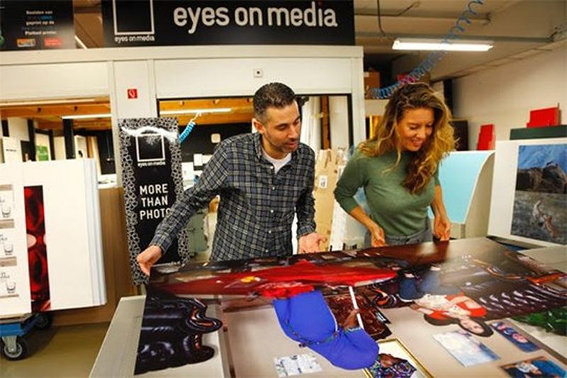 Ilvy Njiokiktjien examines prints with a man at Eyes on Media printers.