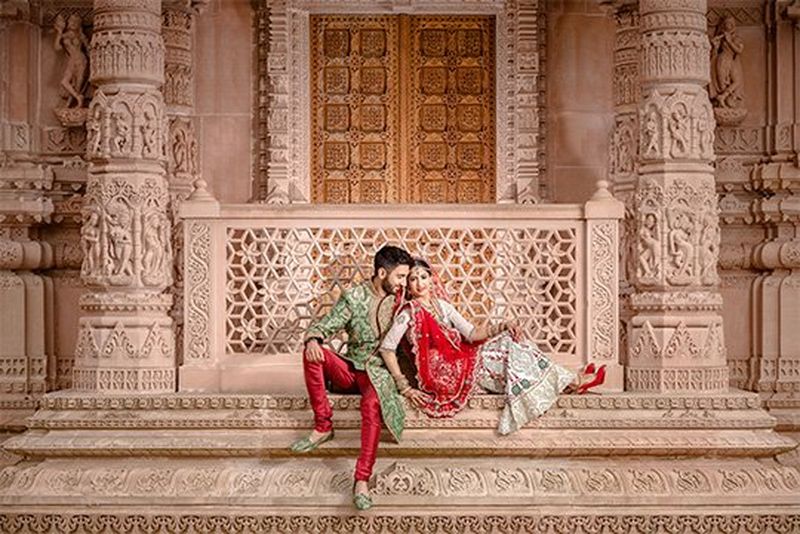 A newlywed couple sit outside the doors of a Hindu temple. Taken by wedding photographer Sanjay Jogia.