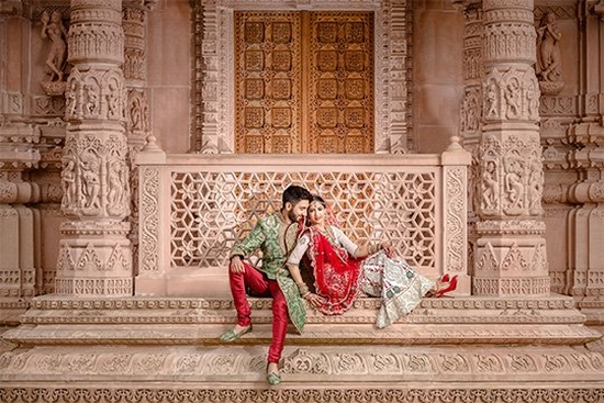 A newlywed couple sit outside the doors of a Hindu temple. Taken by wedding photographer Sanjay Jogia.