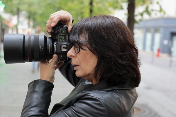 Flicia Sisco holding a Canon ֽ_격- with Canon RF 85mm F1.2L USM DS lens outside.