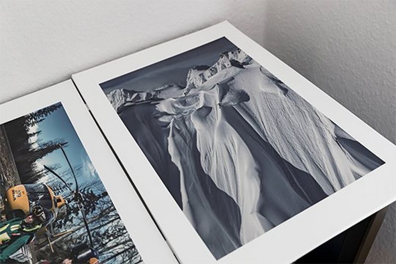 A print of a skier dwarfed by the vast, sheer mountain he is skiing down. Photo by Richard Walch.