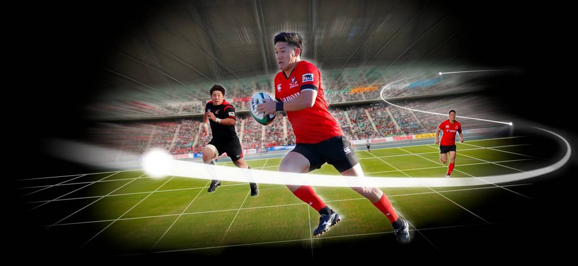 A representation of Canon's Free Viewpoint Video System showing the virtual camera moving freely around the playing field as a rugby player runs with the ball and others chase him. 