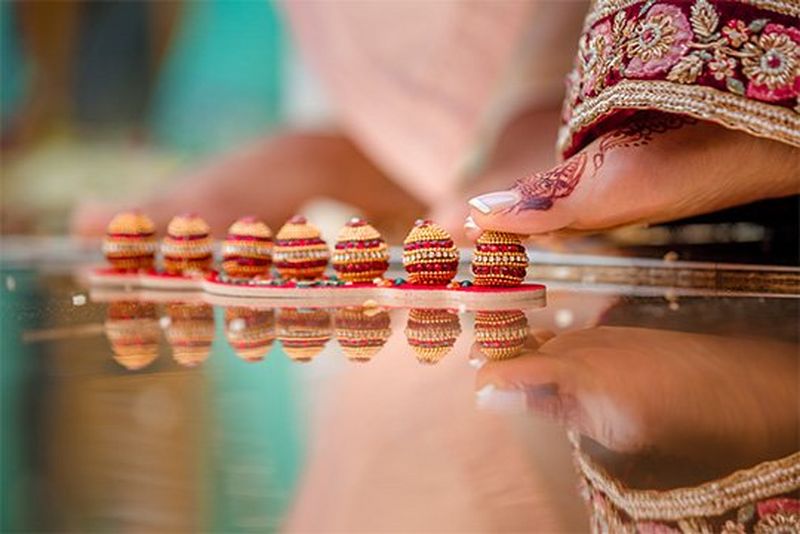 Seven small gold and red pots the size of a big toe are lined up on the floor. A toe begins to step on the first one.