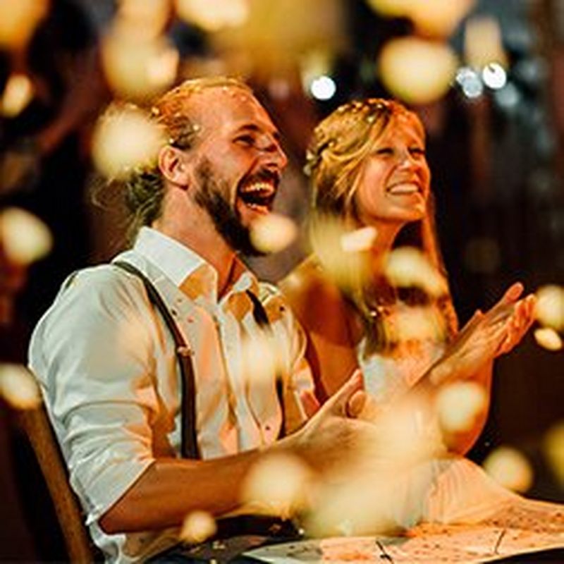 A seated couple laughing in delight as confetti falls around them. Taken by Markus Morawetz.