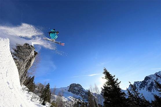 A skier flies into the air off the edge of a mountain. Photo by Martin Bissig.