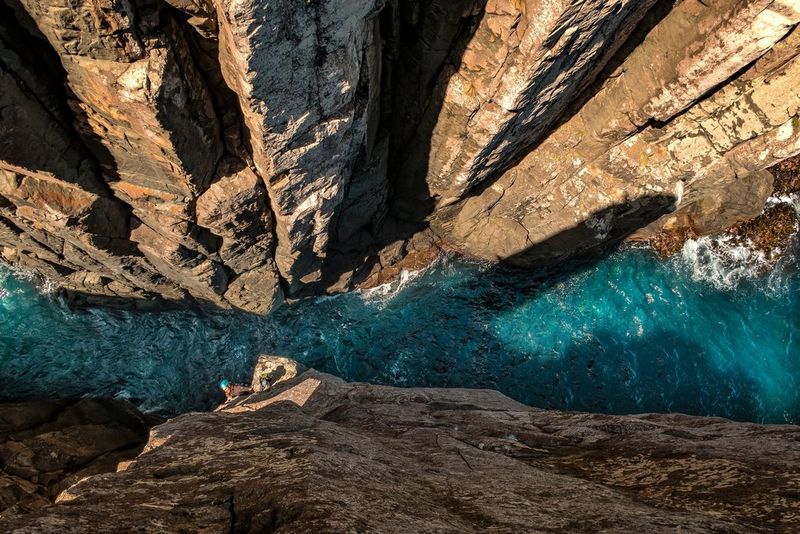 A climber ascending the Totem Pole, a vertical sea stack in the Tasman National Park, Australia.