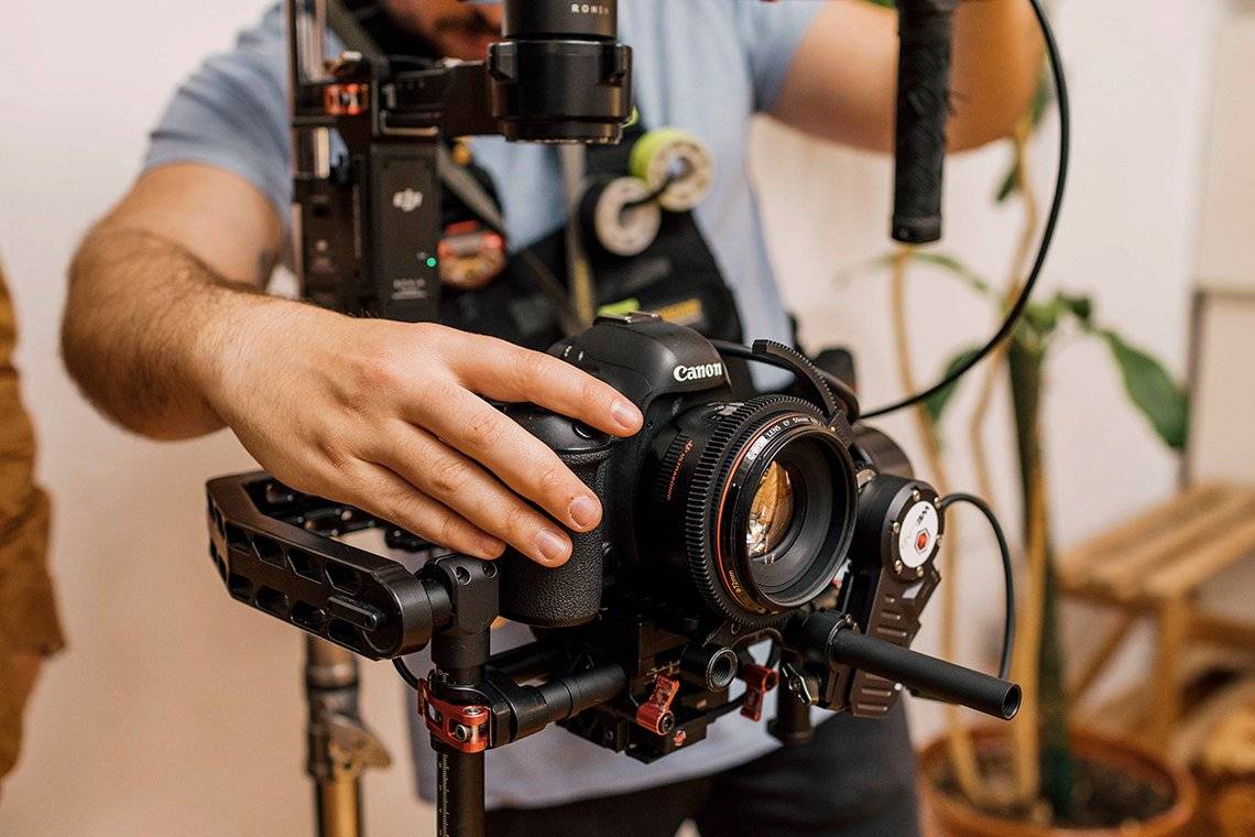 A videographer makes adjustments to a Canon EOS 5D Mark IV on a film set.