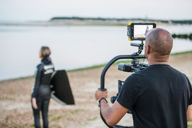 Videographer Simeon Quarrie filming freediver Helena Bourdillon on a beach.