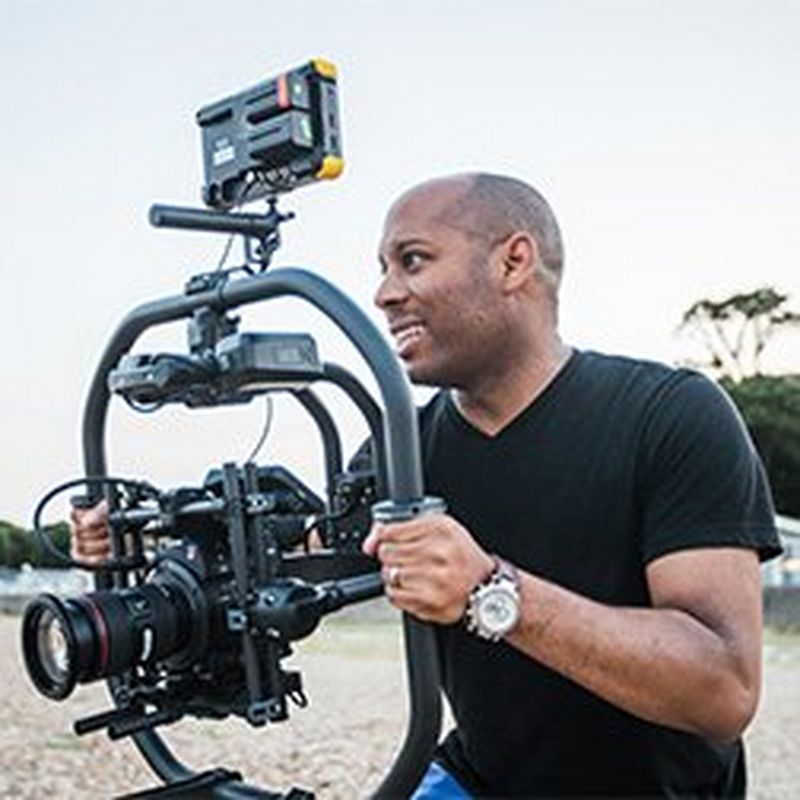 Videographer Simeon Quarrie holding a Canon cine camera attached to a professional gimbal.