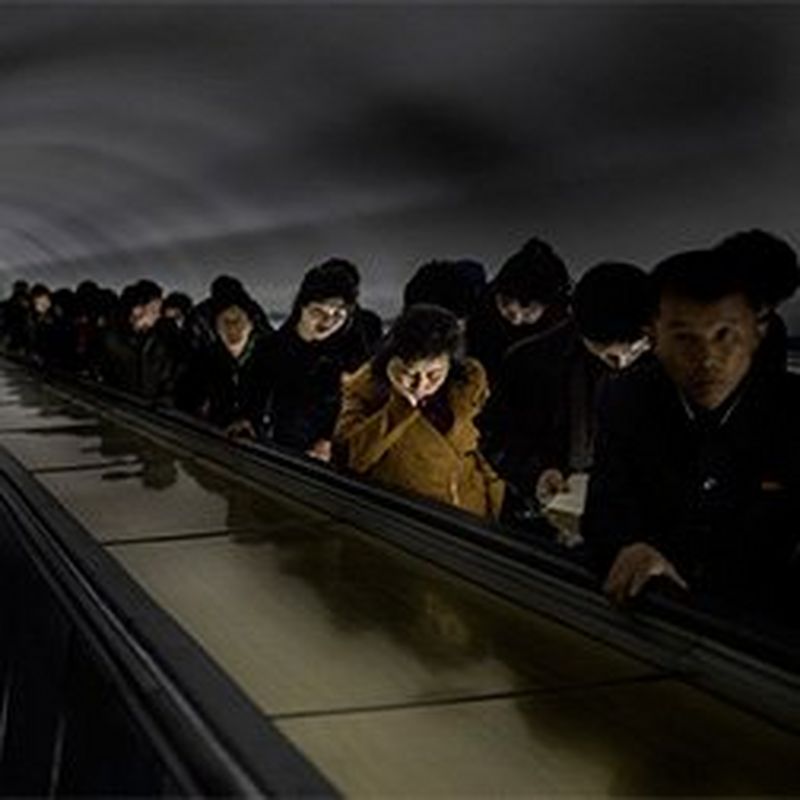 North Korean people travel up a tall metro escalator at rush hour. Photograph by Roger Turesson.