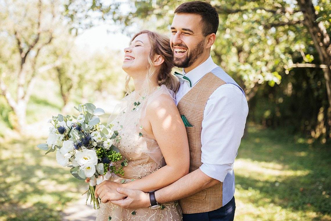 A bride and groom embrace in a garden. Photograph by Marina Karpiy.