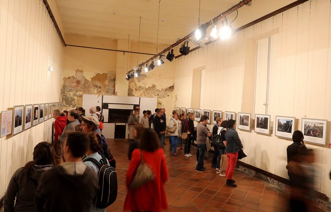 People walk around an exhibition room looking at the printed photographs on the walls.