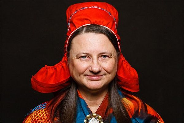 A Finnish woman in traditional costume with a red bonnet.