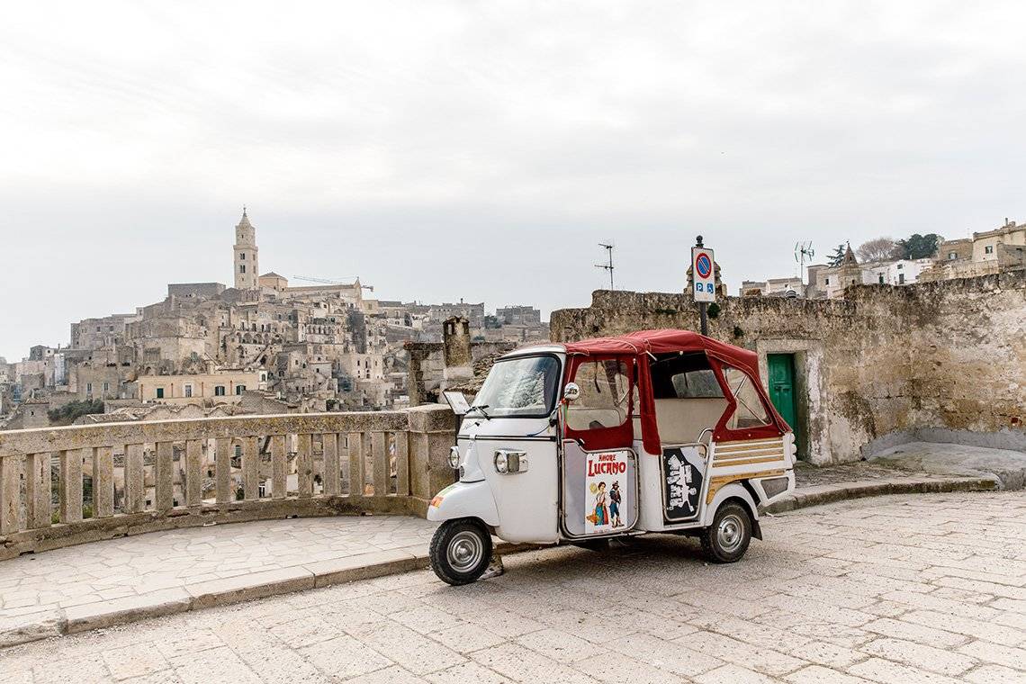 A tuk tuk parked in front of a balcony overlooking the Italian city of Matera. Photo by Annapurna Mellor with a Canon EF 24-70mm f/2.8L II USM.